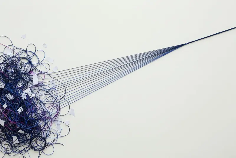 A tangle of navy thread combed into a single straight line